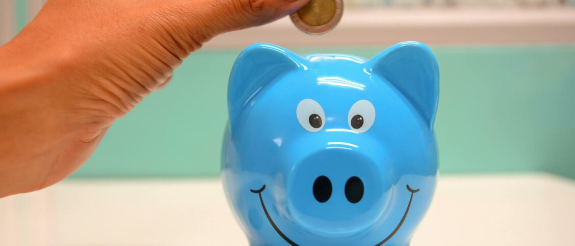 Person Putting Coin in a Piggy Bank