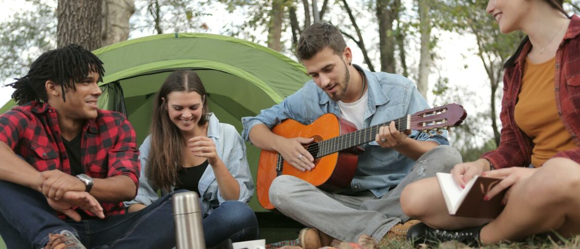 Acoustic Guitar Played By a Man Sitting On Grass Field