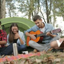 Acoustic Guitar Played By a Man Sitting On Grass Field