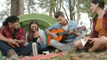 Acoustic Guitar Played By a Man Sitting On Grass Field