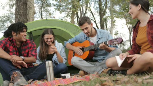 Acoustic Guitar Played By a Man Sitting On Grass Field